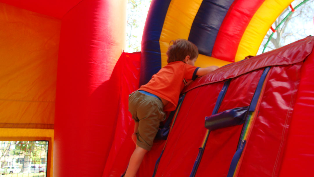 A child climbing the wall of a colorful inflatable obstacle course